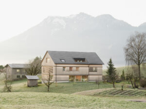 Holzhaus vor Berg umgeben von grünen Wiesen