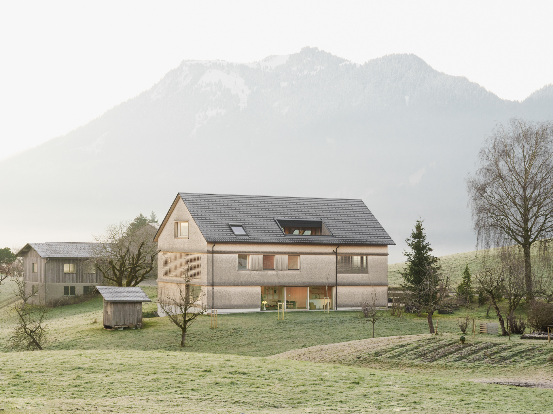 Holzhaus vor Berg umgeben von grünen Wiesen